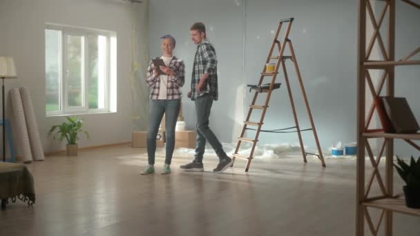 Happy Young Couple Checkered Shirts Using Tablet Plan Renovations Apartment — Vídeos de Stock