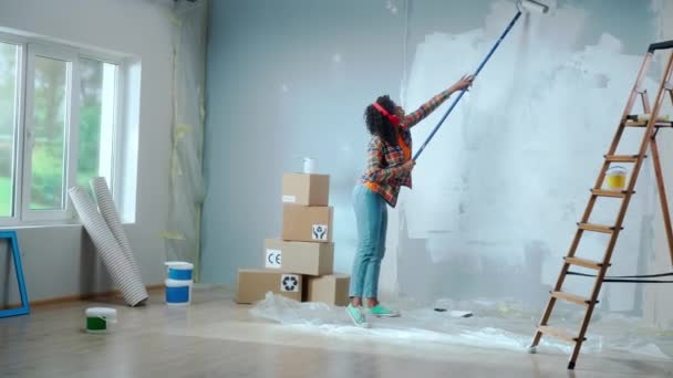 African American Woman Red Headphones Paints Wall White Paint Using — Αρχείο Βίντεο