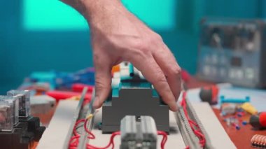 Bir elektrikçi elektromanyetik bobinli bir röleyi doğrudan ve alternatif akımla yükler. Tornavidayla bir adamın ellerine yakın çekim yapmak otomatik elektrik düğmesinde kırmızı kabloyu vidalamaktır.