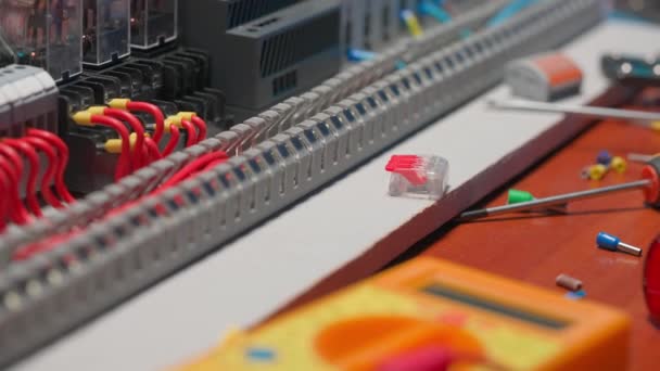 有许多红线和蓝线 电器部件 自动开关 断路器 剩余电流装置的电气面板 靠近桌子上的电源开关 螺丝刀和黄色万用表 — 图库视频影像