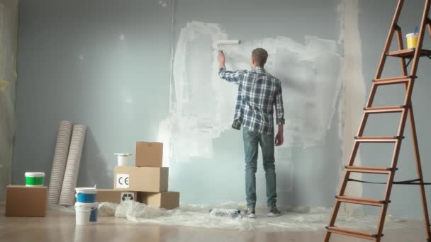 Νεαρός Ζωγραφίζει Τοίχο Λευκή Μπογιά Χρησιμοποιώντας Ρολό Μπογιάς Πίσω Όψη — Αρχείο Βίντεο