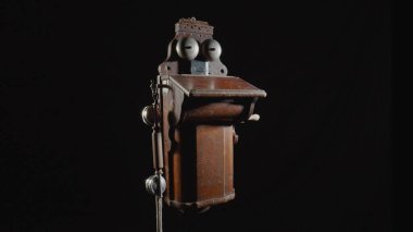 Wooden brown antique telephone apparatus with two metal hemispheres for signaling call. Old school bell. Retro phone with aged handset and mechanism for loud chime. Vintage shabby phone on isolated