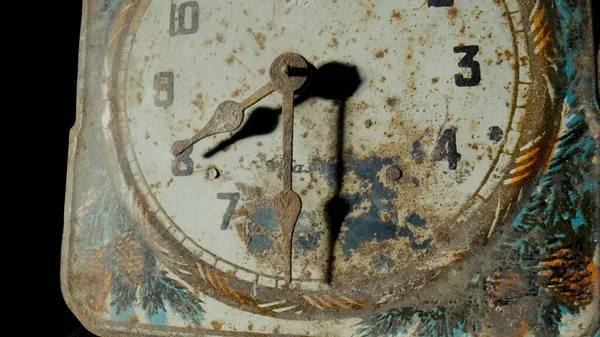 Old clock dial with rusty minute and hour hands covered corrosion. White face of vintage watch with weathered pattern, scuffs and scratches. Broken retro clock on a black isolated studio background
