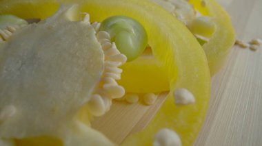 Sliced rings of fresh raw yellow bell peppers on wooden board. Sweet pepper slices with seeds and juicy pulp in macro shot. Background of ripe vegetables for restaurant. Ripe juicy pepper for salad