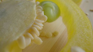 Sliced rings of fresh raw yellow bell peppers on wooden board. Sweet pepper slices with seeds and juicy pulp in macro shot. Background of ripe vegetables for restaurant. Ripe juicy pepper for salad