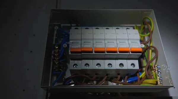 White electrical panel with many wires, electrical parts, automatic switches, breakers, residual current devices, fuses, terminals. High voltage automatic breaker switch, close up in the dark
