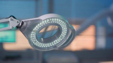 Round magnifier lamp with spot LEDs. White glowing lamp on a blurred blue background close up. Equipment for lighting and magnifying objects in a beauty salon or laboratory