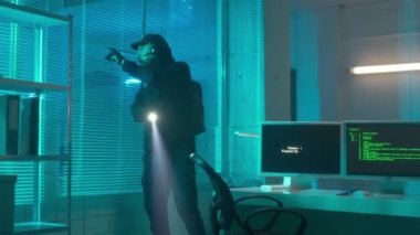 A hacker in a black hoodie and gloves is spying in the laboratory, typing on a computer keyboard. A man downloads a virus to computer and the infection rate starts counting down. The source code and a