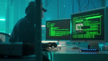 Beyaz maskeli bir hacker bir bilgisayar klavyesine yazıp şifre kırıyor. Siyah kapüşonlu, eldivenli ve kulaklıklı bir adam güvenlik sistemlerini hackliyor. Ekranda yeşil bir kod çizgisi beliriyor