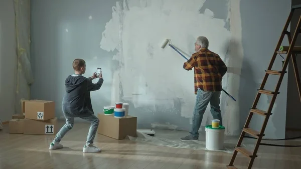 Grandson Takes Photo Mobile Phone Filming Video Grandpa Painting Wall — Stockfoto