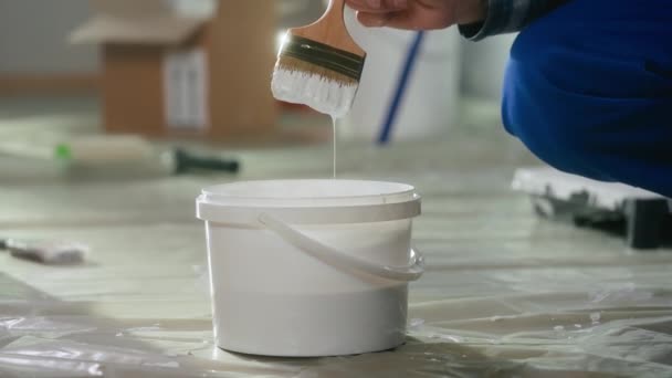 Unrecognizable Man Dips Brush Bucket White Paint Stirs Plastic Pail — Stock video