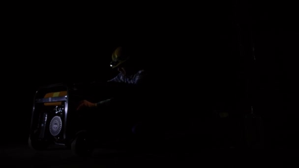 Человек Синем Комбинезоне Жёлтом Шлеме Темноте Включает Бензиновый Генератор Загорается — стоковое видео
