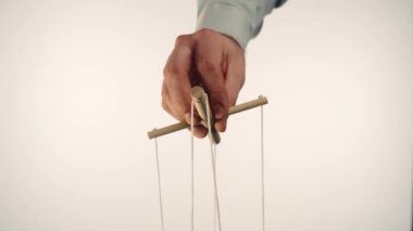 The puppeteers hand controls the puppet with a wooden manipulator and strings. The marionettist controls and pulls the strings on a white isolated background. Concept of dependence, dominance