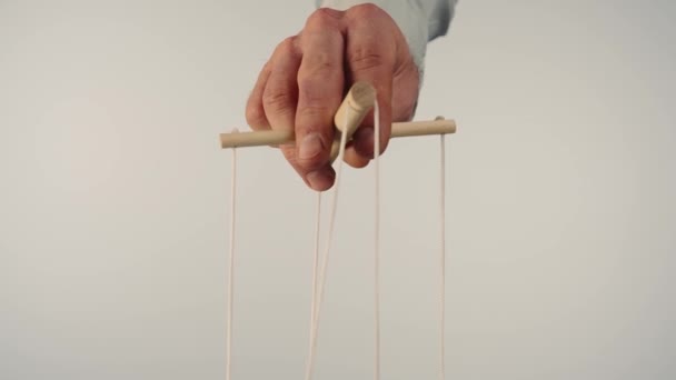 人形遣いは人形を木製のマニピュレータと弦で操作します マリオンティストは 文字列を白い孤立した背景で制御し 引っ張ります 依存と支配の概念 — ストック動画