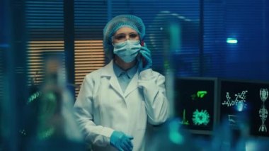 Woman doctor talking on a mobile phone, inspecting and counting medical equipment. Female scientist in white gown, goggles, mask and gloves in a laboratory or hospital with blue light. View through a