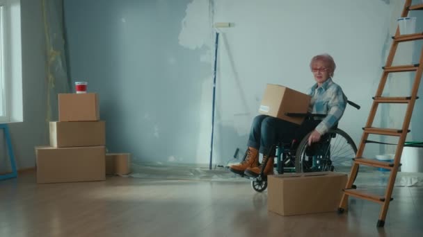 Elderly Disabled Woman Moves Wheelchair Cardboard Box Granny Puts Box — Vídeos de Stock