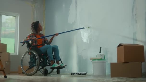 African American Woman Wheelchair Paints Wall White Paint Using Long — Stockvideo