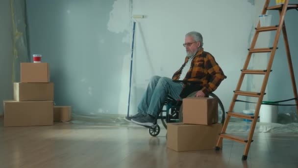 Elderly Disabled Man Moves Wheelchair Cardboard Box Pensioner Puts Box — Vídeos de Stock