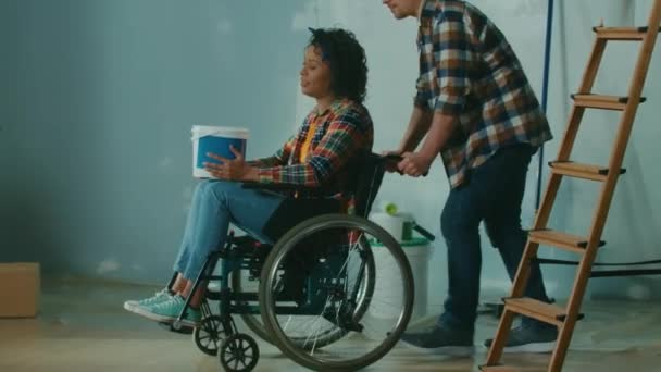 White Man Wheeling African American Woman Room Wheelchair Bucket Paint — Vídeos de Stock