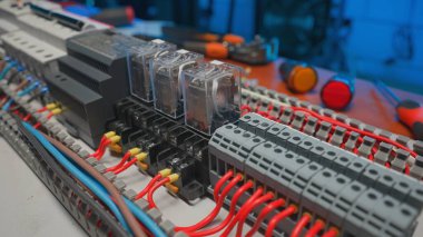 Electrical panel with many red and blue wires, electrical parts, automatic switches, breakers, residual current devices. Close up of a electrical switch on a table in an electrical workshop
