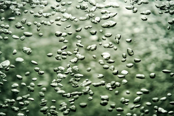 A stream of shiny air bubbles illuminated by light and shining on a dark background. Close up of light lit oxygen bubbles flow upwards. Aeration or filtration of liquid. Fizzy flow of air bubbles