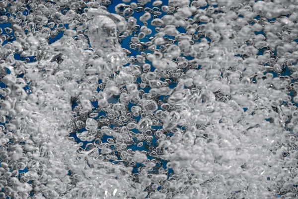 Proud Lesklých Vzduchových Bublin Ozářených Světlem Zářících Modrém Pozadí Zblízka — Stock fotografie