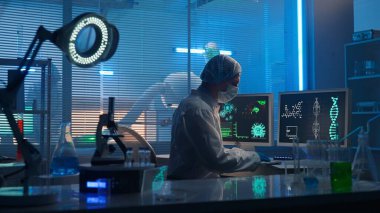 Medical development laboratory. A male scientist types on a keyboard and enters research data. A male researcher against the backdrop of a modern laboratory with test tubes, flasks and a microscope