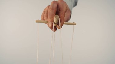 Kuklacılar, tahta bir manipülatör ve tellerle kuklayı kontrol eder. Kuklacı beyaz izole bir arka planda ipleri kontrol eder ve çeker. Bağımlılık kavramı, egemenlik