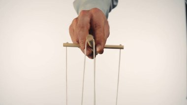 Kuklacılar, tahta bir manipülatör ve tellerle kuklayı kontrol eder. Kuklacı beyaz izole bir arka planda ipleri kontrol eder ve çeker. Bağımlılık kavramı, egemenlik
