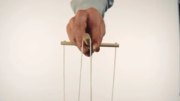 The puppeteers hand controls the puppet with a wooden manipulator and strings. The marionettist controls and pulls the strings on a white isolated background. Concept of dependence, dominance