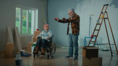 Yaşlı bir adam ve tekerlekli sandalyedeki yaşlı bir kadın. Yaşlı bir çift iletişim kuruyor ve onarımları planlıyor. Penceresi, merdiveni, karton kutuları, boya kovaları, silindirleri ve fırçaları olan bir oda. Konsept