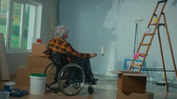 Tekerlekli Sandalyedeki Yaşlı Engelli Bir Adam Elinde Boya Silindiri Olan — Stok fotoğraf