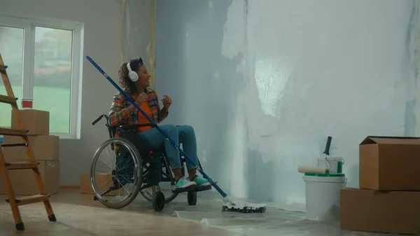 Afroamerykanka Białych Słuchawkach Wózku Maluje Ścianę Białą Farbą Długim Wałkiem — Zdjęcie stockowe