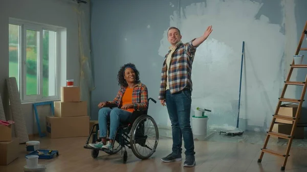 Valkoinen Mies Afroamerikkalainen Nainen Pyörätuolissa Nuori Pari Suunnittelee Huoneen Korjausta — kuvapankkivalokuva