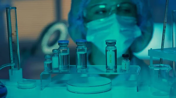 여인의 유리병 시험관을 검사한다 실험실이나 병원에서 광선을 마스크 장갑을 연구원들 — 스톡 사진
