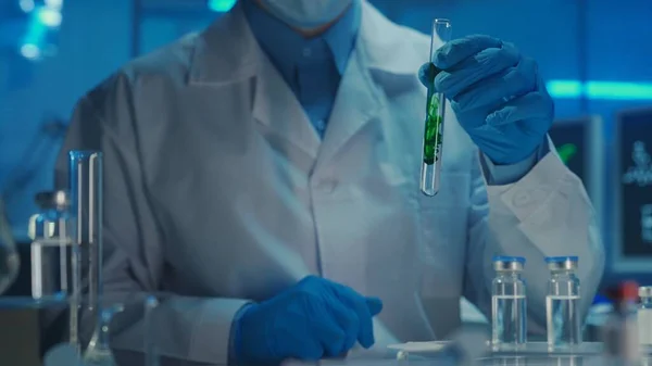 白いコートと青い手袋の男性医師は 彼の手に透明な液体中に溶解緑の物質とガラス試験管を保持しています 試料の研究 化学反応 近代生化学 — ストック写真