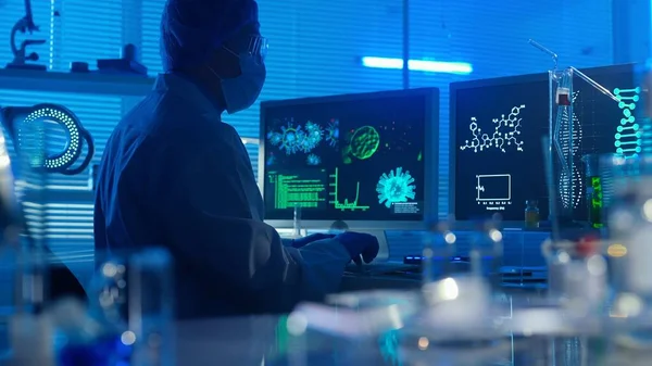 电脑键盘上一个身穿白色长袍的男人的深色轮廓 一位男性研究人员 背景在一个配备了试管 瓶和显微镜的现代实验室 医疗发展 — 图库照片