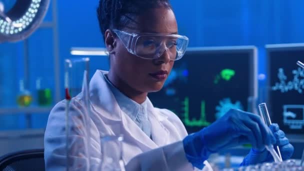 플라스틱 피펫을 사용하는 아프리카 미국의한 여인은 액체를 시험관에 표본을 검사하였다 — 비디오