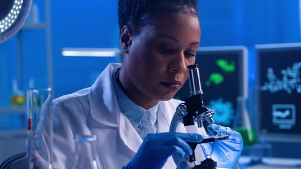 Ung Afrikansk Amerikansk Kvinde Undersøger Eksemplar Mikroskop Justerer Øjenstykke Sort – Stock-video