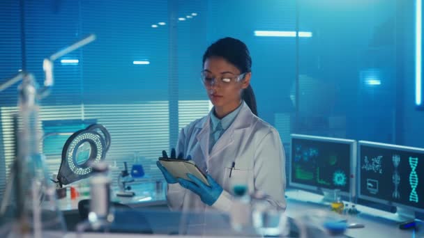 亚洲女医生使用数码平板电脑 浏览资讯 身穿白色医疗服和护目镜的韩国籍女性实验室助理 蓝光实验室或医院 — 图库视频影像
