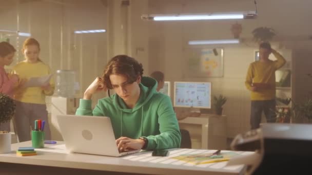 Mladý Muž Mluví Pomocí Sluchátek Píše Klávesnici Notebooku Zatímco Sedí — Stock video