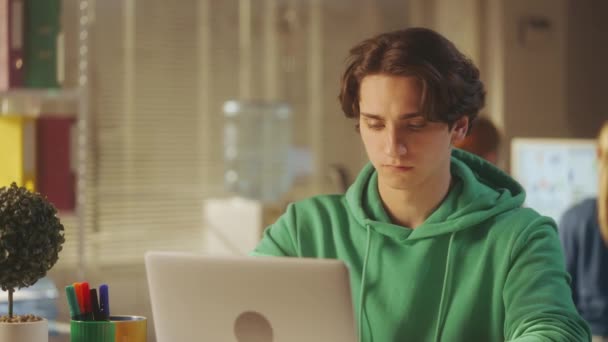 Портрет Молодого Человека Зеленой Толстовке Печатающего Клавиатуре Ноутбука Затем Смотрящего — стоковое видео