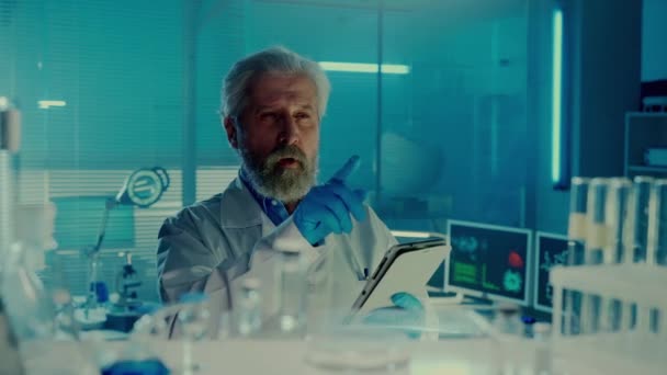 高齢男性医師は在庫や注文薬を取り デジタルタブレットにデータを入力します 青い光の研究室の白い医療用コートの固体男性科学者 棚からの眺め — ストック動画