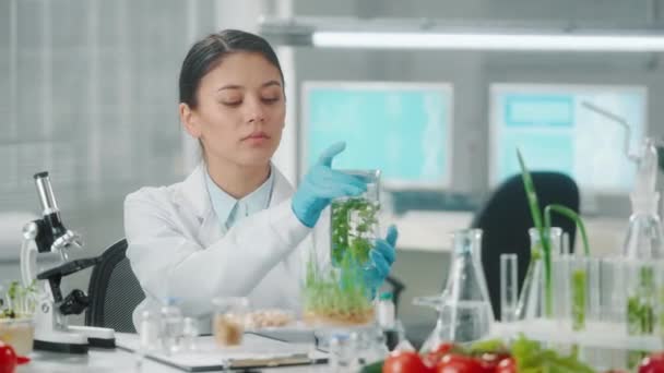 Asian Female Researcher Examines Green Seedlings Flask Takes Notes Microbiologist — Stock Video