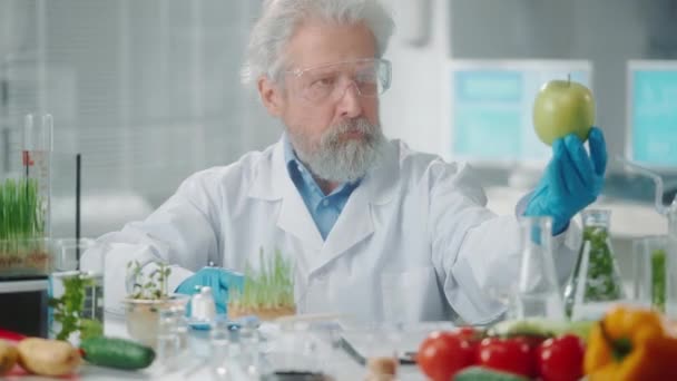 老年男性研究人员对一个青苹果样本进行了研究 并编写了数据 生物技术专家分析样品的质量 蔬菜和绿芽的生物学实验 — 图库视频影像