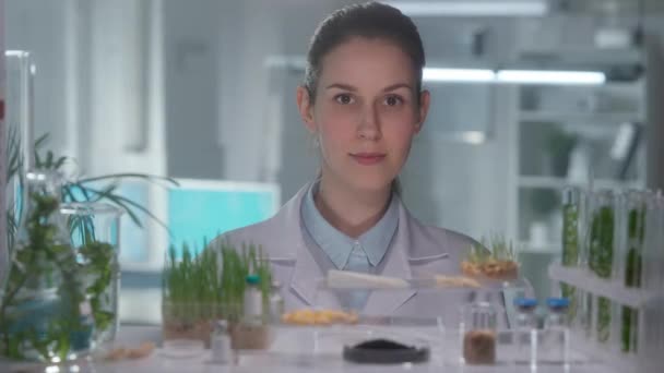 Beyaz Önlüklü Kadın Araştırmacı Kameraya Bakıp Gülümsüyor Bitkilerin Matara Test — Stok video