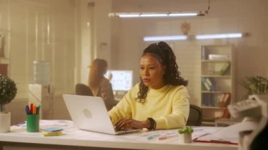 Genç bir Afro-Amerikalı kadın dizüstü bilgisayarda klavye kullanıyor ve sonra da onu hayal kırıklığına uğratarak kapatıyor. Sarı kazaklı siyah kadın programcı ya da tasarımcı ofiste bir masada oturuyor. Yönetim ekibi.