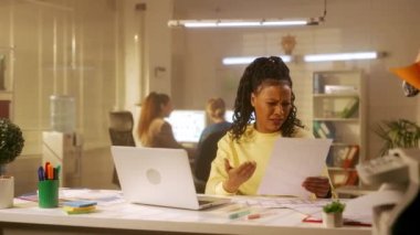 Genç bir Afrikalı Amerikalı kadın dizüstü bilgisayardaki ve kağıt tablolardaki bilgilere bakıyor ve çok üzgün. Kızgın siyah kadın öfkeyle bir kağıt parçasını buruşturur ve çöpe atar. Yönetim.