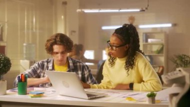 Afrikalı bir Amerikalı kadın ve Avrupalı bir erkek yeni bir projeyi tartışıyorlar. Ofis çalışanları dizüstü bilgisayardaki ve kağıt tablolarındaki verileri kontrol ediyor. Yönetim ekibi arka planda çalışıyor. Ofis kavramı