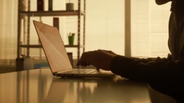 Laptop klavyesine yazı yazan bir adamın karanlık yüzü, işini bitirir ve kapatır. Siyah gömlekli bir erkek yönetici, tasarımcı veya programcı karanlık bir ofiste masada otururken çalışır.